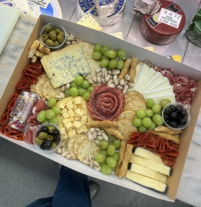 The Blue & Brie Grazing Box - A beautifully balanced grazing box featuring creamy Brie wedges, bold blue cheese, aged cheddar cubes, and charcoal rind slices. Served with cured meats, crackers, pistachios, green & black olives, and fresh grapes. Perfect for 4–6 cheese lovers.